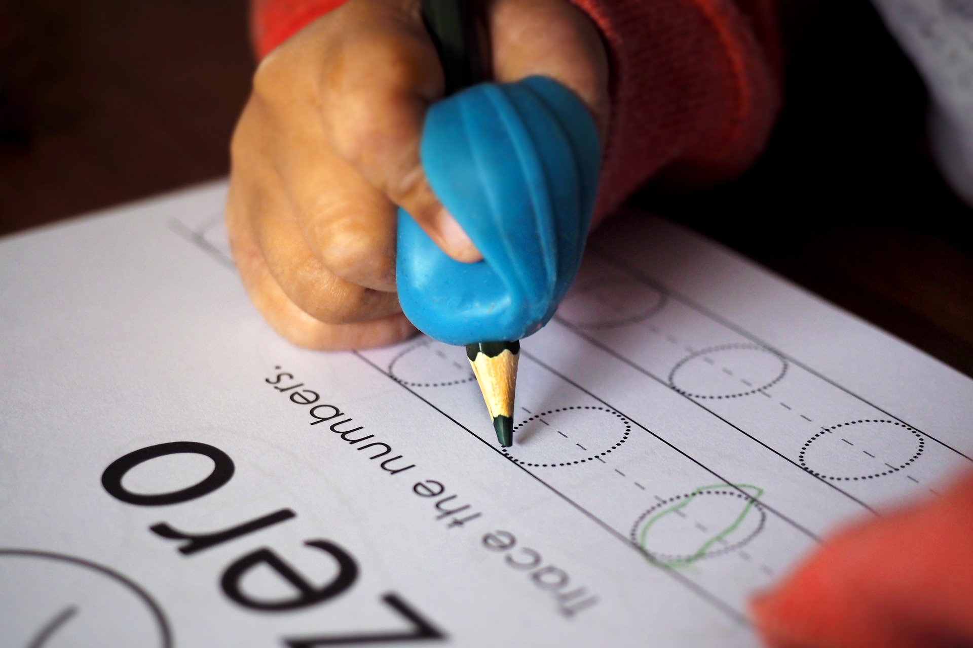 Child practicing writing '0'