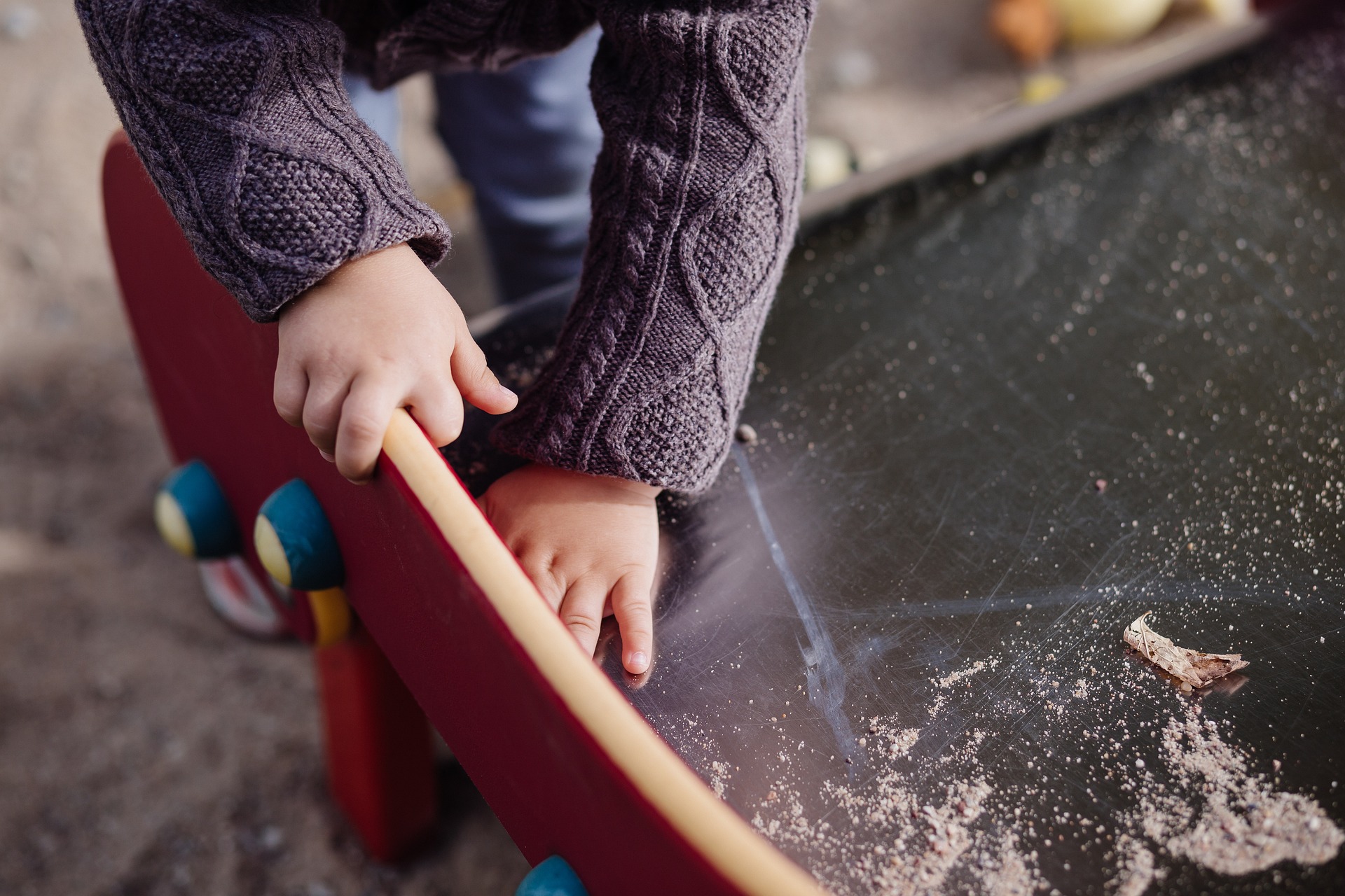 Child clearing spilt sand